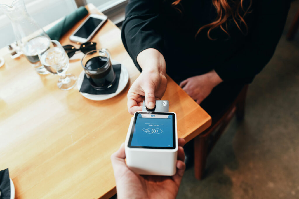 A woman inserting her card into a card reader while a waiter holds the payment terminal.