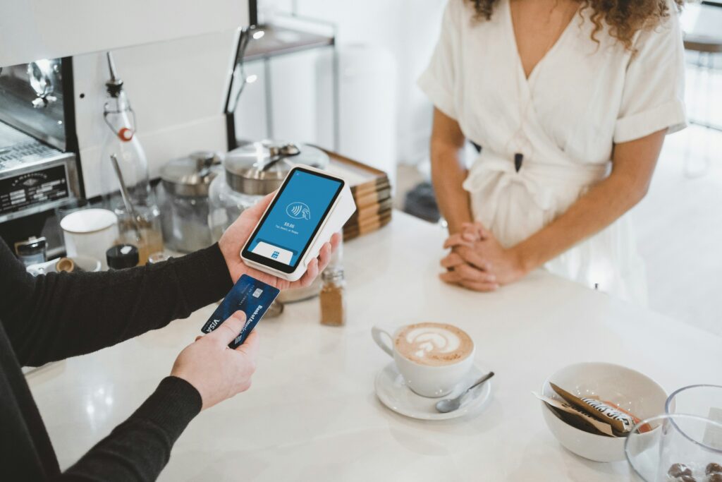 A customer making a contactless payment while a cashier holds the card reader behind the counter.