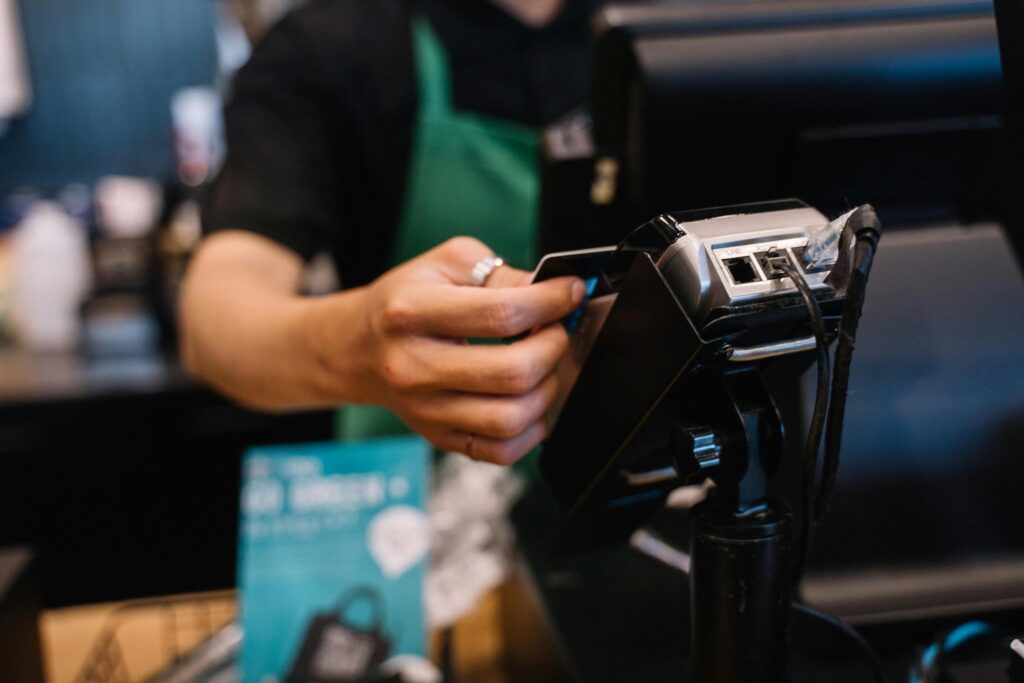 Waiter processing contactless card payment on modern card machine in Irish restaurant