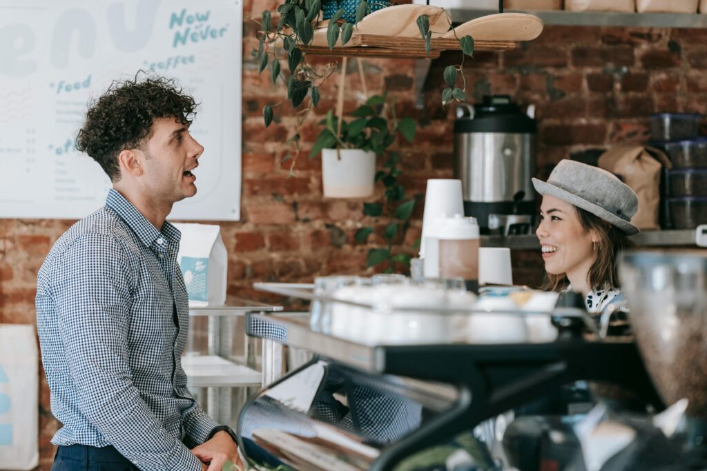 A customer ordering at the counter while a smiling waiter listens attentively.