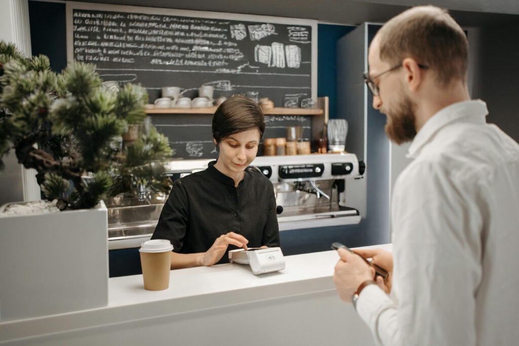 Small business owner comparing card machine costs on tablet in Irish coffee shop