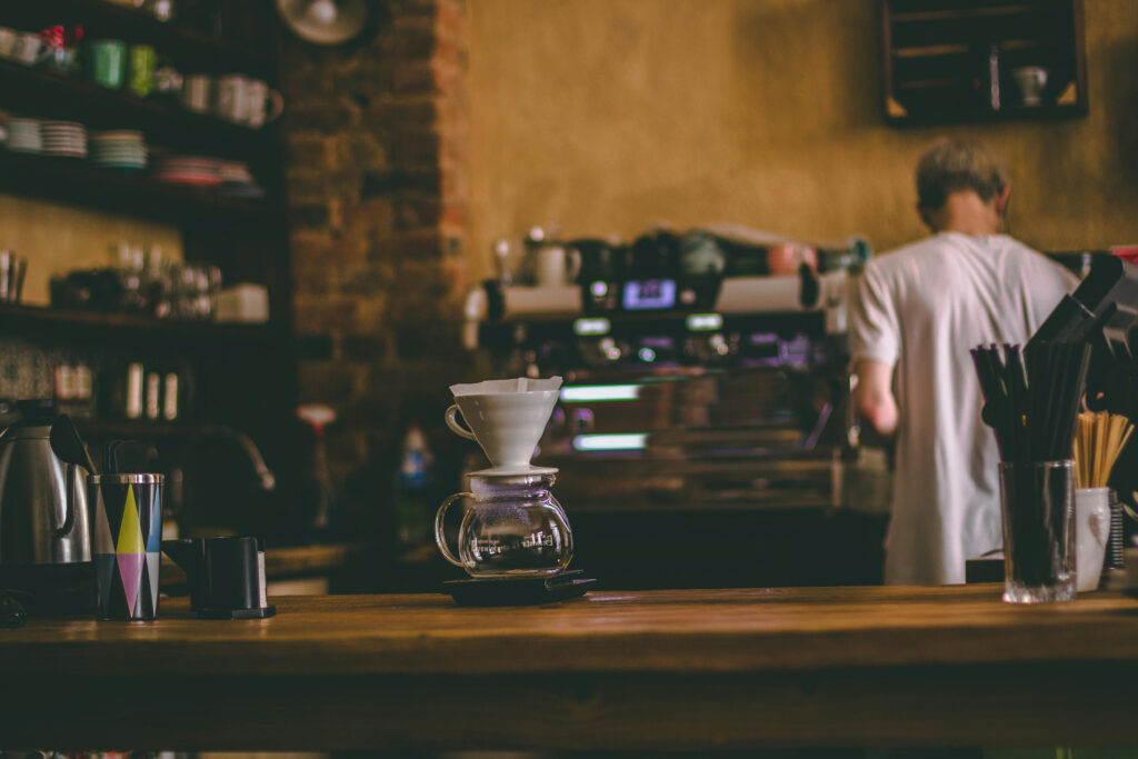 Barista calculating cost comparison of payment processing options while preparing coffee