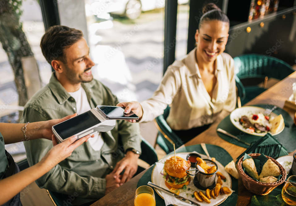 Person making contactless payment with smartphone mobile payment app in Dublin cafe